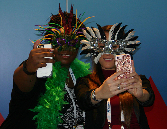 people in feathered masks taking selfies