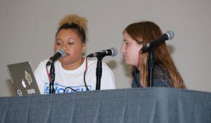 two teens at table in front of microphones