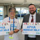 smiling man and woman holding Monday Mile signs