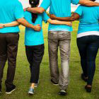 backs of four people walking arm in arm