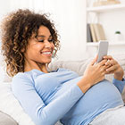 smiling pregnant woman looking at laptop
