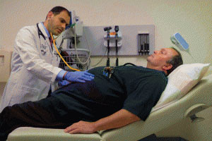 doctor examining man in hospital bed