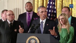 Barack Obama at White House lectern surrounded by people