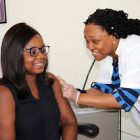 smiling nurse gives smiling woman a flu shot