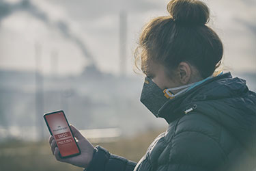 Masked woman near polluting factory