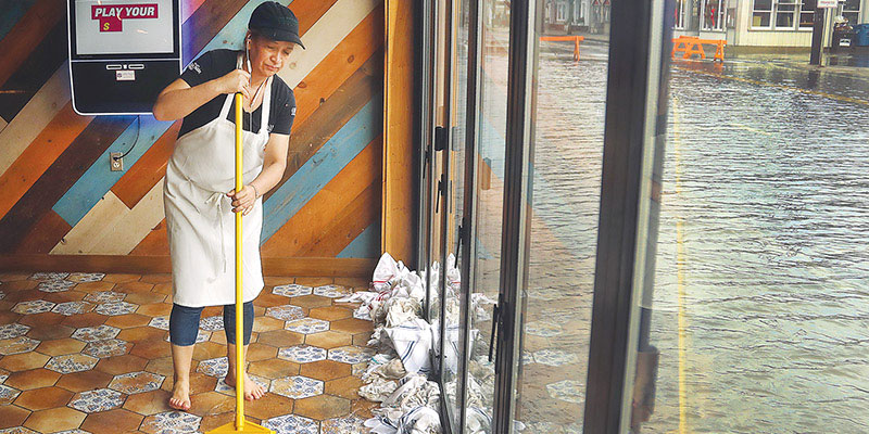 A worker sweeps up floodwater at a business