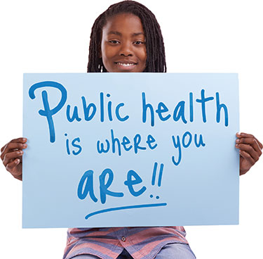 Woman holds sign saying, Public Health is Where You Are