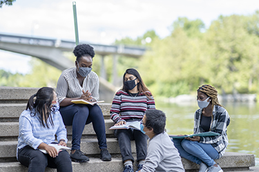 Teens socialize while wearing masks.