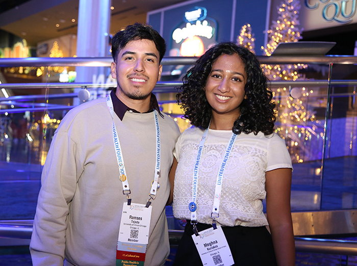 A man and woman stand facing the camera and smiling. 