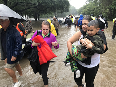 People walk through a flooded area during a storm