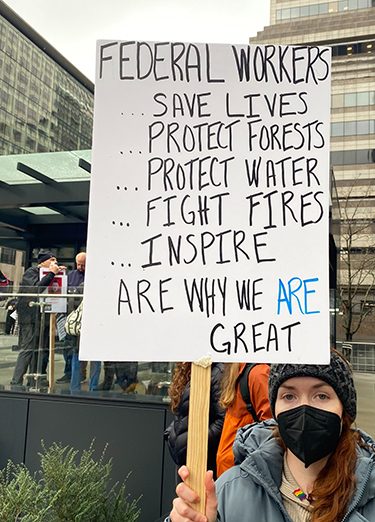 A protestor shows a sign in support of federal workers.