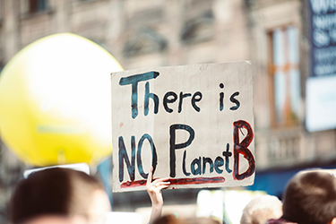 At a protest a hand is holding up a sign that says There Is No Planet B.