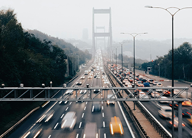 Cars and trucks zoom by on a busy highway nearing a bridge