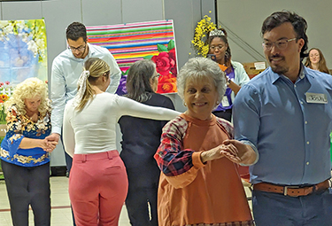 Younger people dance with older people at a ballroom-style event