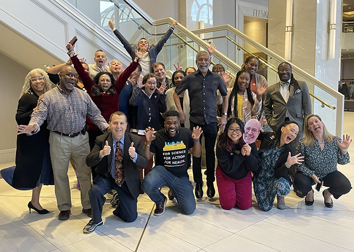 About 20 members of the 2024 APHA Executive Board pose for the camera, some laughing and raising their arms or making silly faces. 