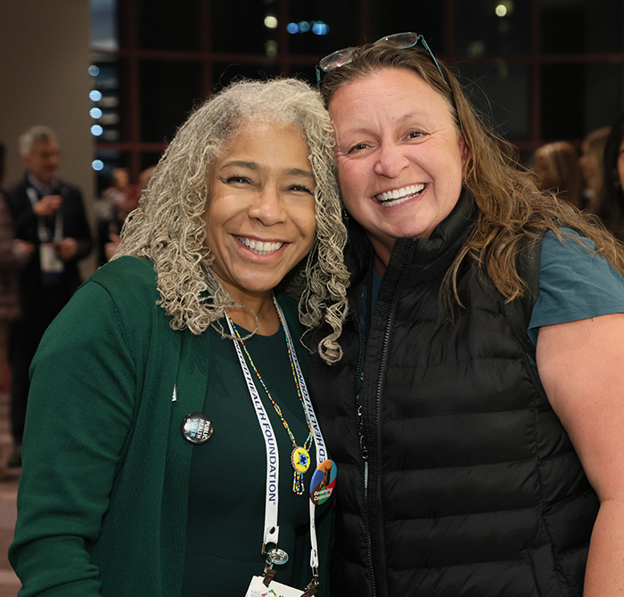 APHA President-elect Deanna Wathington, on the left, leans in toward another woman, their heads touching as they smile and face camera. 