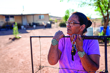 An American Indian woman stands outside her ranch house