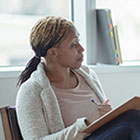 A woman therapist holds a clipboard while providing counseling to a woman.