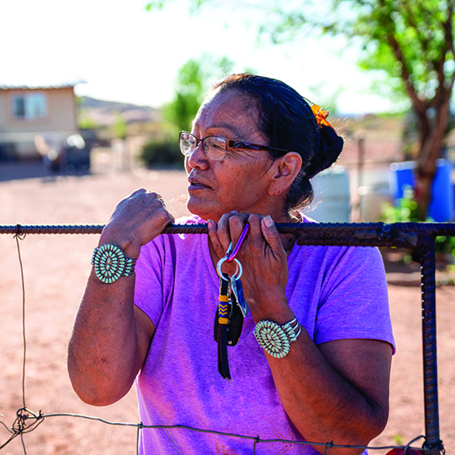 An American Indian woman stands outside her ranch house