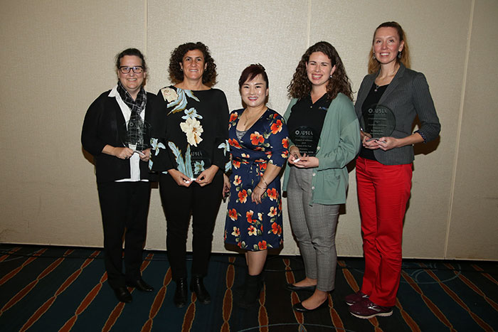five smiling women displaying awards